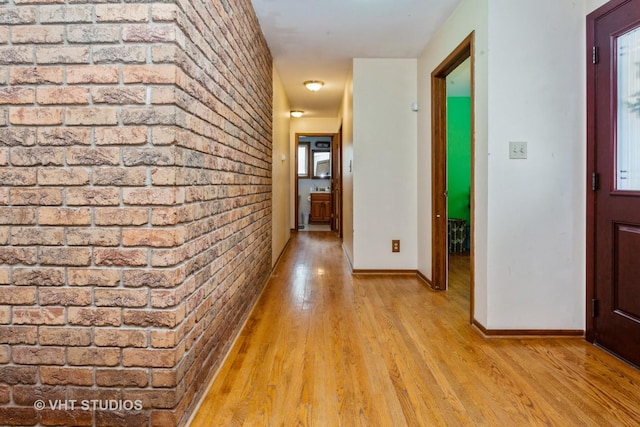 hall featuring brick wall and light hardwood / wood-style floors