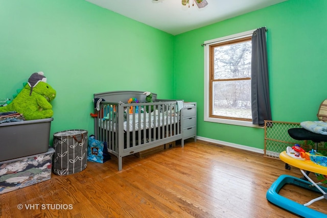 bedroom featuring a crib and light hardwood / wood-style flooring