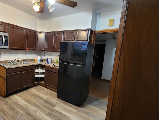 kitchen featuring sink, light hardwood / wood-style floors, decorative backsplash, black refrigerator, and ornamental molding