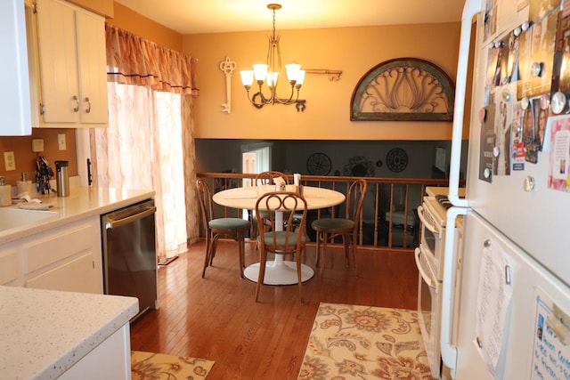 kitchen with white appliances, white cabinets, decorative light fixtures, an inviting chandelier, and light hardwood / wood-style flooring