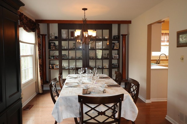 dining space featuring sink, hardwood / wood-style floors, and a notable chandelier