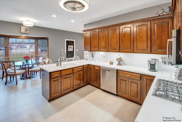 kitchen with sink, kitchen peninsula, decorative backsplash, light tile patterned flooring, and appliances with stainless steel finishes