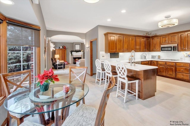 kitchen with kitchen peninsula, a kitchen breakfast bar, backsplash, sink, and stovetop