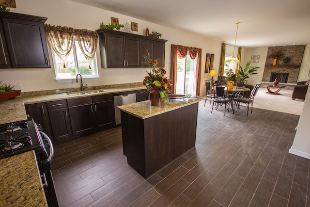 kitchen with stainless steel dishwasher, dark wood-type flooring, sink, range, and a kitchen island