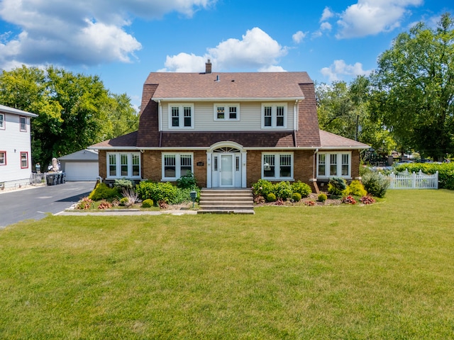 view of front of property with a garage, an outdoor structure, and a front lawn