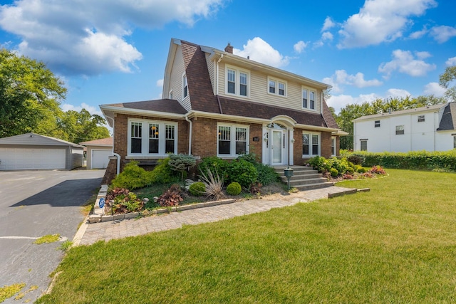 view of front of property featuring a garage, an outdoor structure, and a front lawn