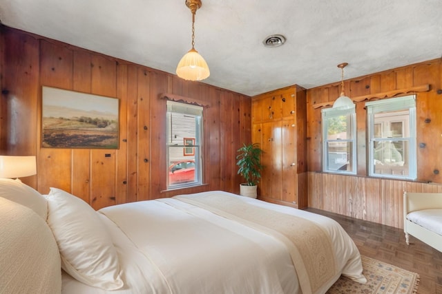 bedroom featuring parquet floors and wooden walls