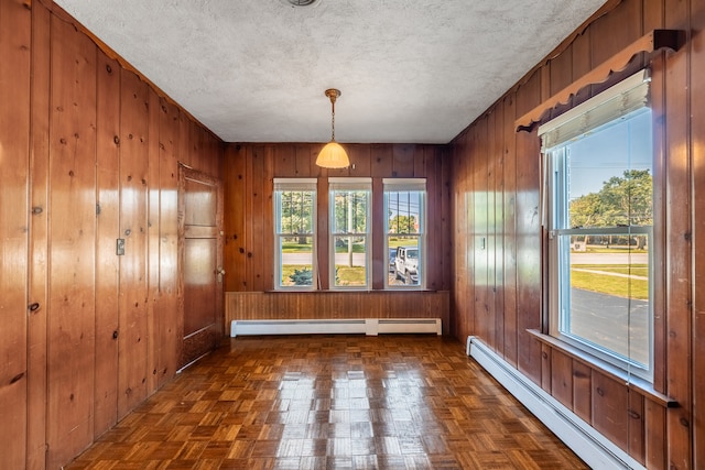 unfurnished dining area featuring wooden walls and a baseboard heating unit