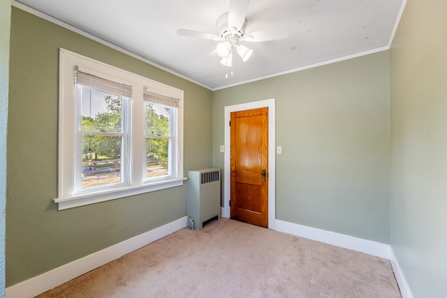 carpeted empty room with ceiling fan, radiator heating unit, and crown molding