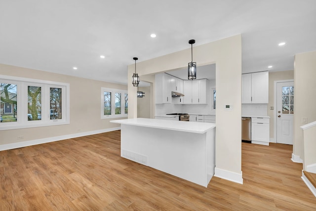 kitchen with pendant lighting, white cabinets, light wood-type flooring, tasteful backsplash, and stainless steel appliances