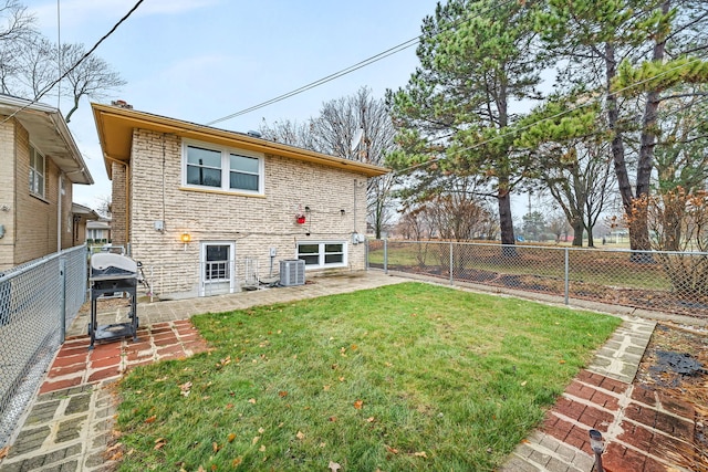 rear view of house with central AC, a patio area, and a lawn