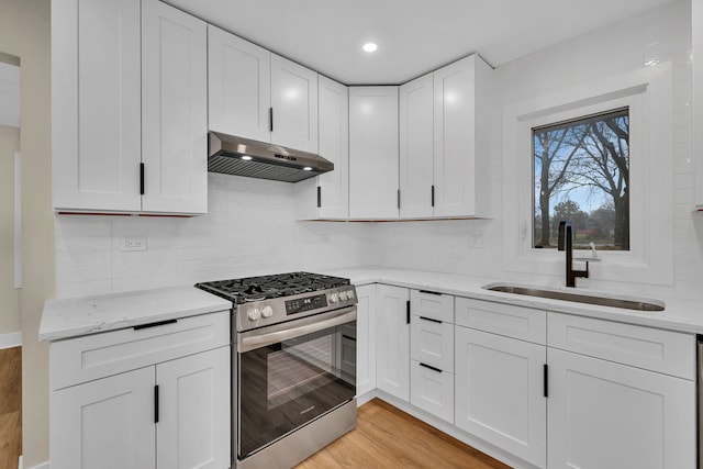 kitchen with sink, light hardwood / wood-style flooring, stainless steel gas stove, white cabinetry, and extractor fan