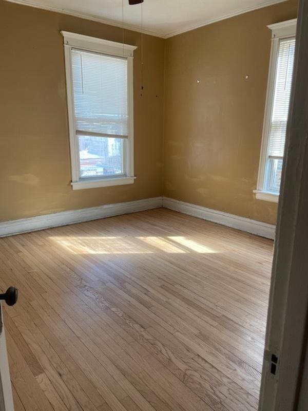 spare room featuring ornamental molding, a ceiling fan, baseboards, and hardwood / wood-style floors