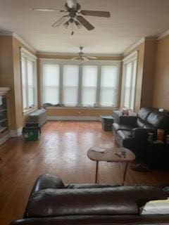 living room featuring wood finished floors, ornamental molding, and a ceiling fan