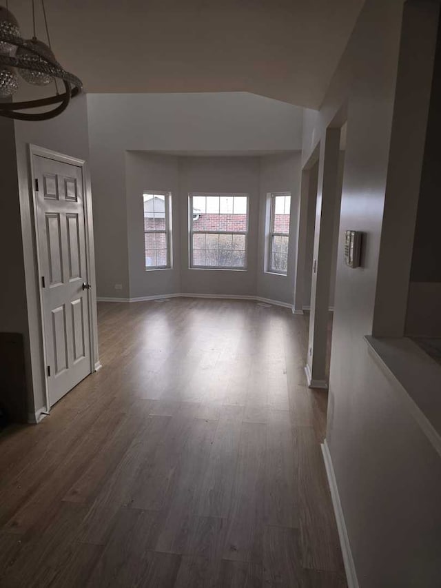 spare room with dark wood-type flooring and lofted ceiling