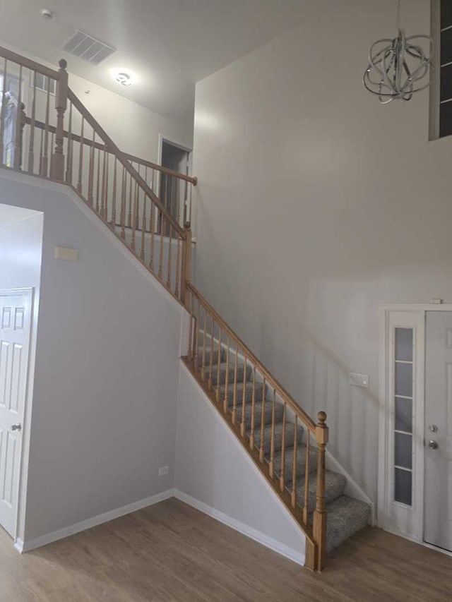 stairs with hardwood / wood-style floors and an inviting chandelier