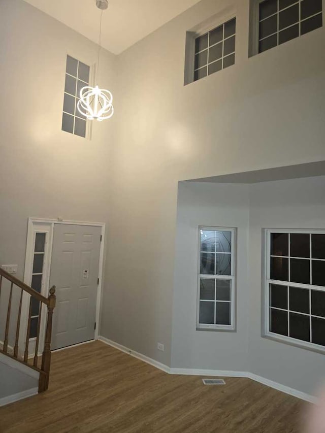 entrance foyer with wood-type flooring, a high ceiling, and a notable chandelier