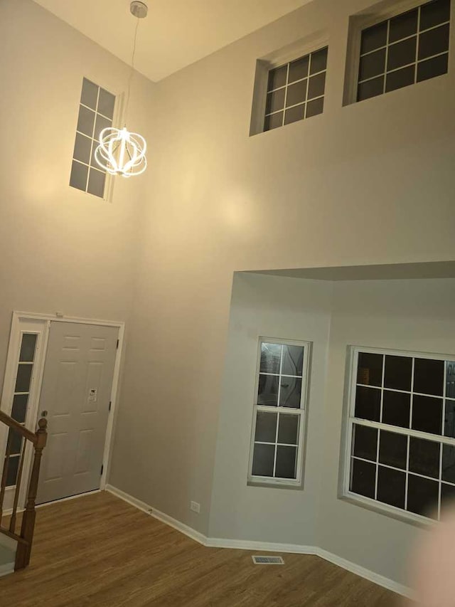 entrance foyer with a towering ceiling, hardwood / wood-style flooring, and an inviting chandelier