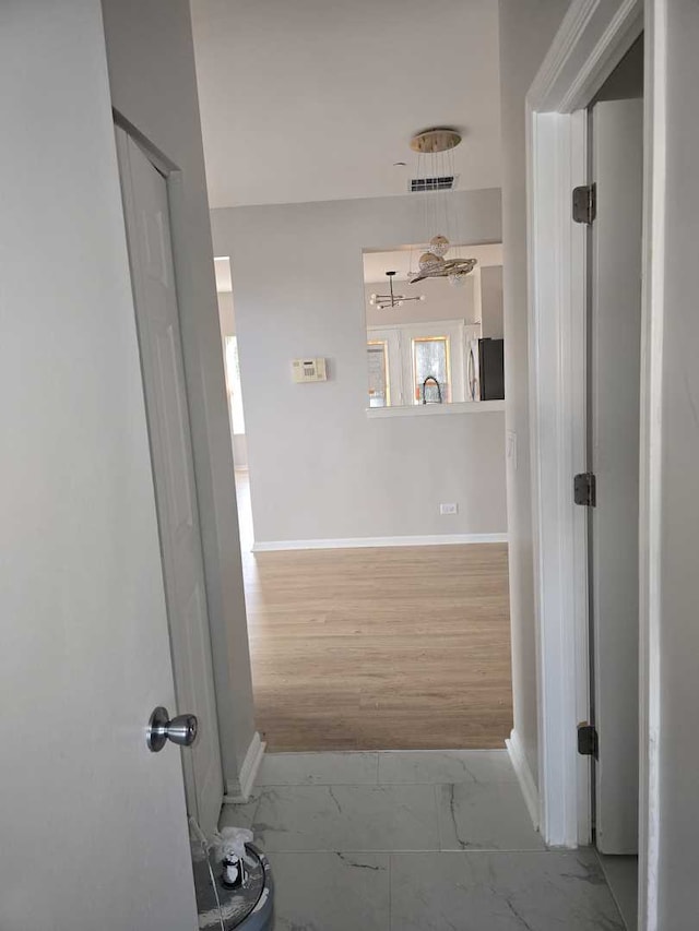 hall featuring an inviting chandelier, light hardwood / wood-style flooring, and sink