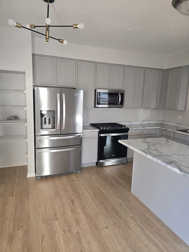 kitchen featuring stainless steel appliances, light hardwood / wood-style flooring, gray cabinetry, and light stone counters