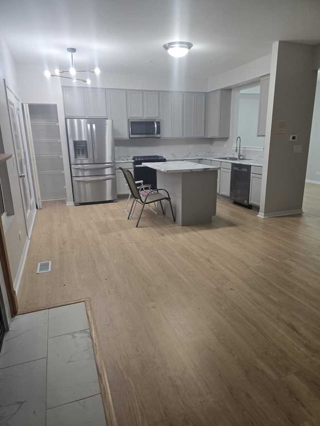 kitchen featuring a breakfast bar, a center island, black appliances, sink, and light hardwood / wood-style floors