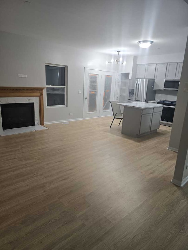 kitchen featuring light wood-type flooring, appliances with stainless steel finishes, a center island, and decorative light fixtures