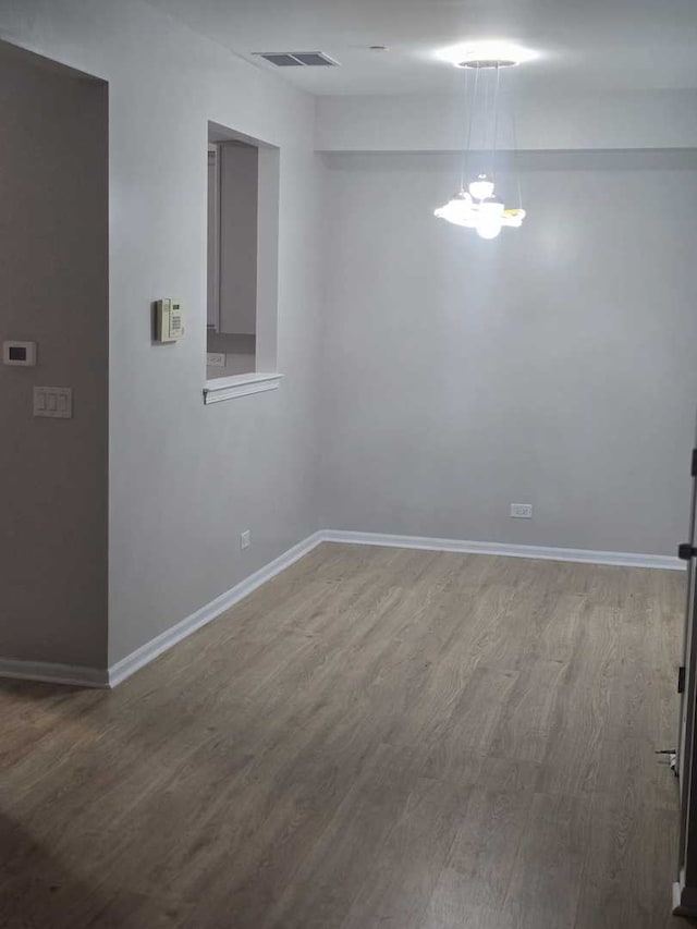 empty room with a chandelier and hardwood / wood-style flooring