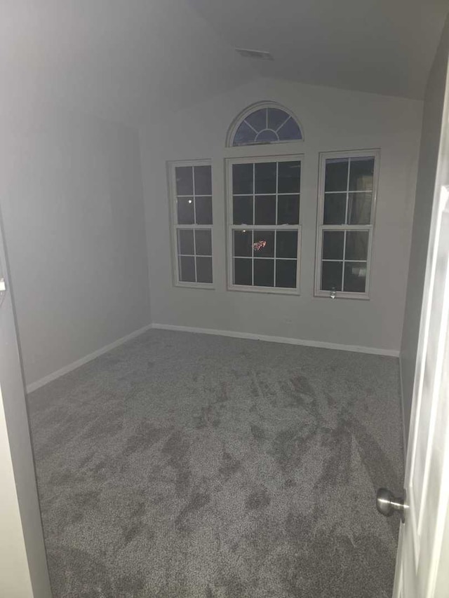 carpeted empty room featuring vaulted ceiling