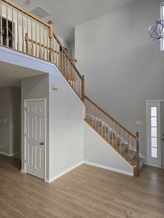 staircase featuring hardwood / wood-style floors, a towering ceiling, and a notable chandelier