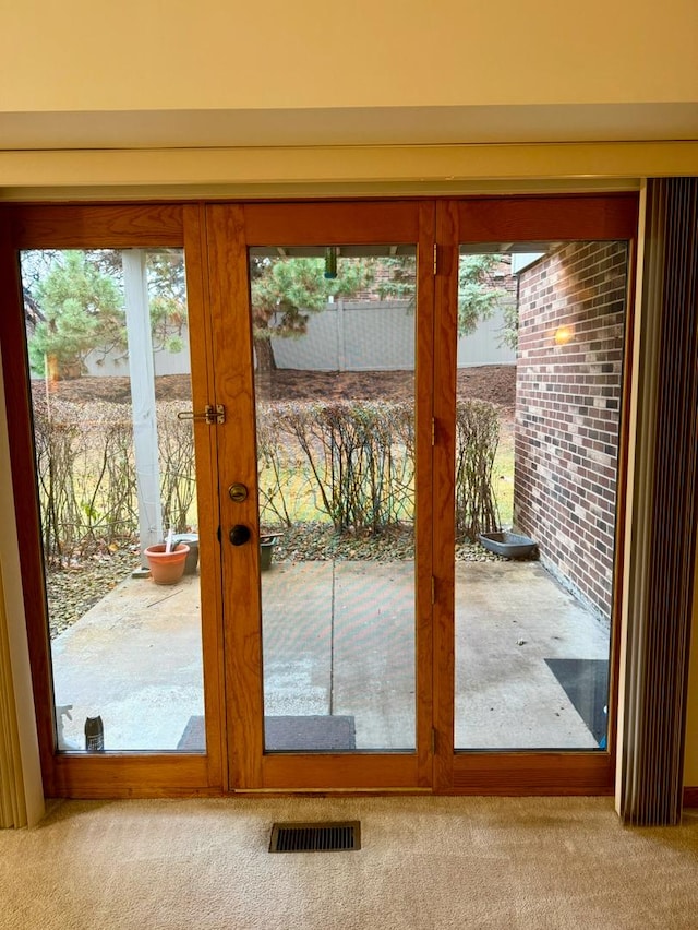 doorway to outside with light carpet, french doors, and a healthy amount of sunlight