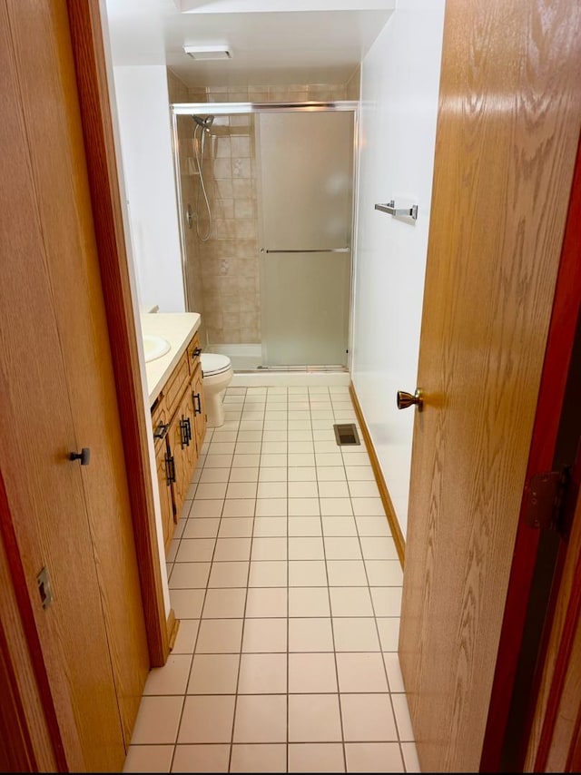 bathroom featuring toilet, tile patterned flooring, vanity, and walk in shower