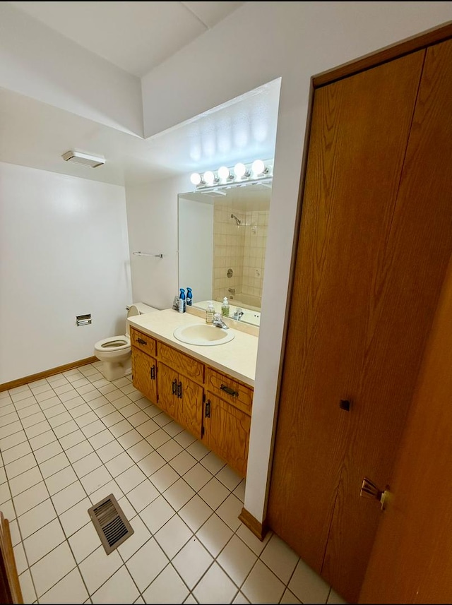 bathroom with tiled shower, tile patterned flooring, vanity, and toilet