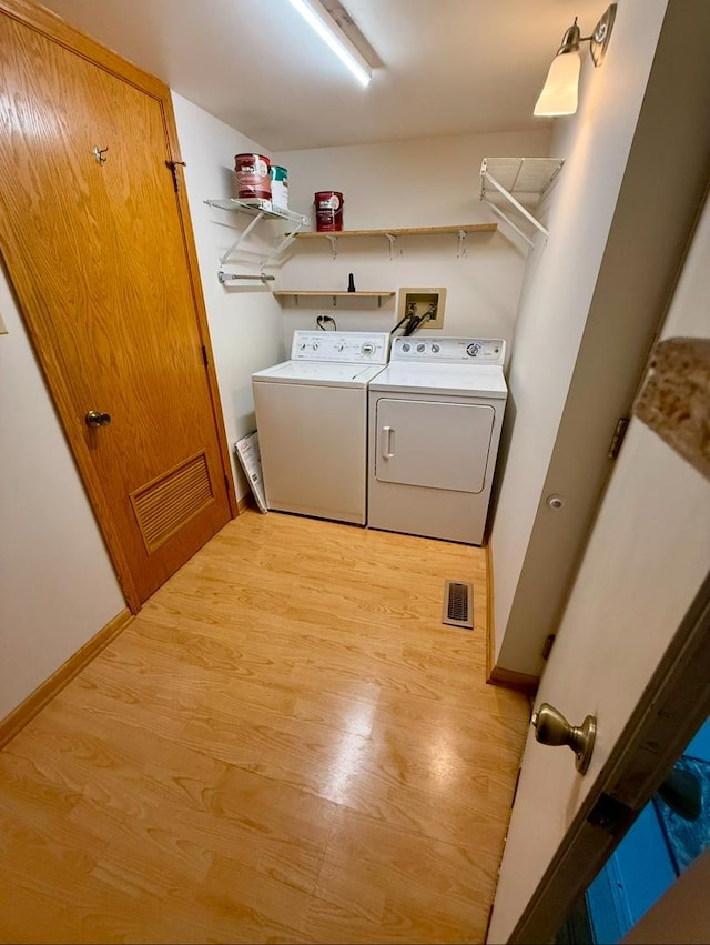 laundry area with washing machine and dryer and light hardwood / wood-style flooring