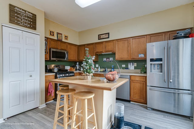 kitchen with a center island, stainless steel appliances, a breakfast bar area, and light hardwood / wood-style flooring