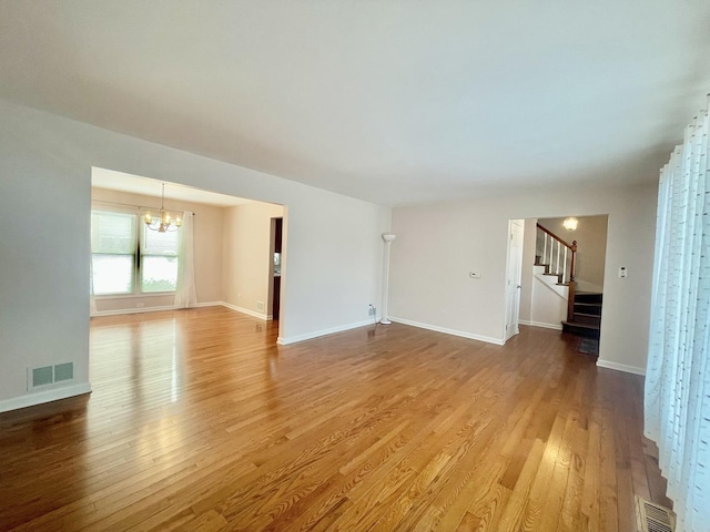 unfurnished living room featuring a chandelier and hardwood / wood-style floors