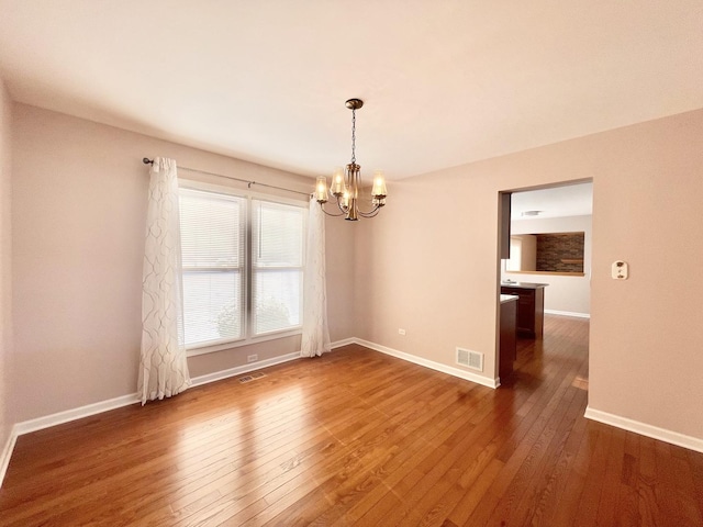 empty room featuring dark wood-type flooring and an inviting chandelier