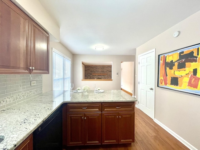 kitchen featuring black dishwasher, tasteful backsplash, wood-type flooring, light stone countertops, and kitchen peninsula