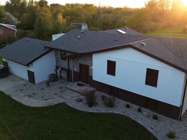 back house at dusk featuring a lawn and cooling unit