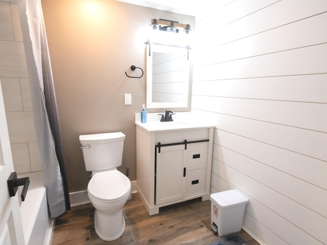 full bathroom with shower / bath combo with shower curtain, hardwood / wood-style floors, vanity, and toilet