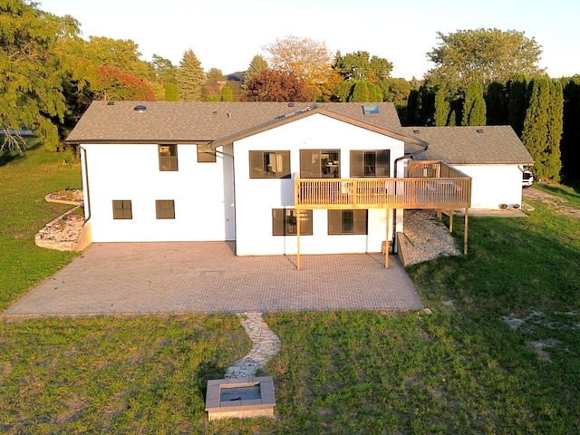 rear view of house with a patio, a lawn, and a wooden deck