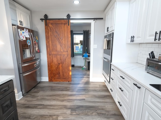 kitchen with white cabinets, a barn door, stainless steel appliances, and dark wood-type flooring