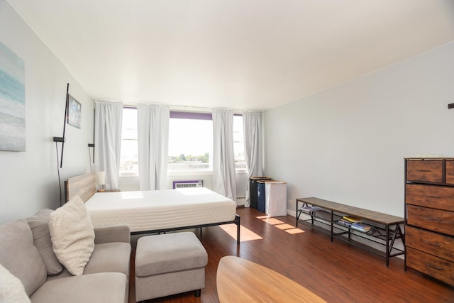 bedroom with hardwood / wood-style floors and a baseboard heating unit