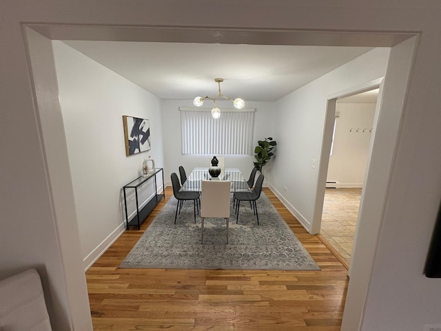 dining area featuring a baseboard heating unit, wood-type flooring, and a chandelier