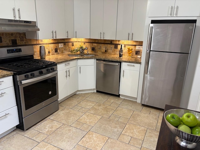 kitchen with sink, backsplash, dark stone countertops, white cabinets, and appliances with stainless steel finishes