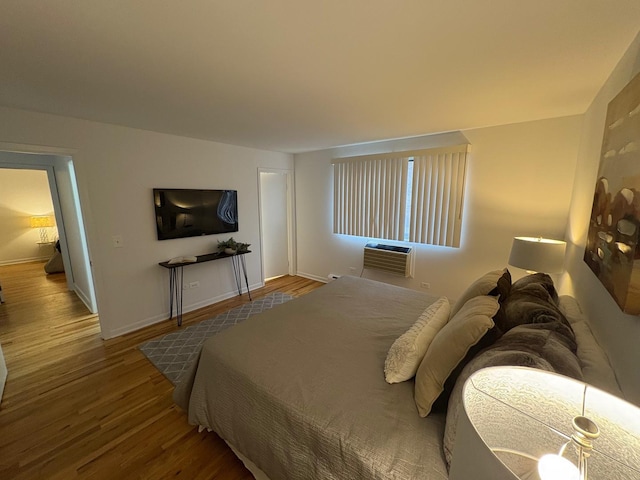 bedroom with a wall mounted AC and hardwood / wood-style floors