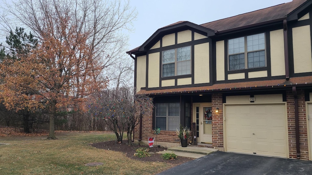 english style home featuring a garage and a front lawn