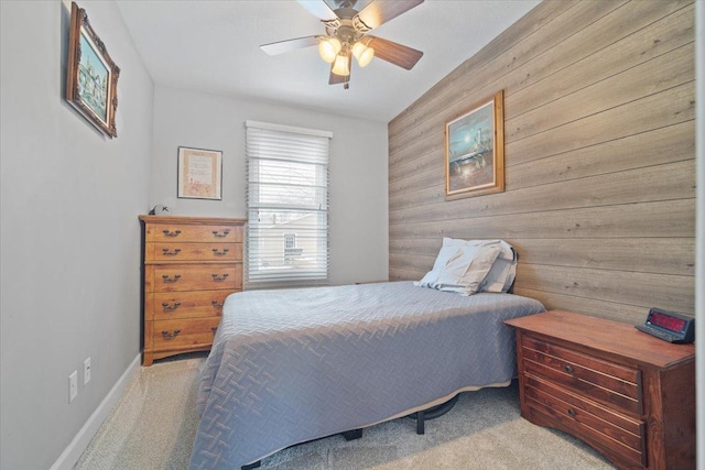 carpeted bedroom featuring ceiling fan and wooden walls