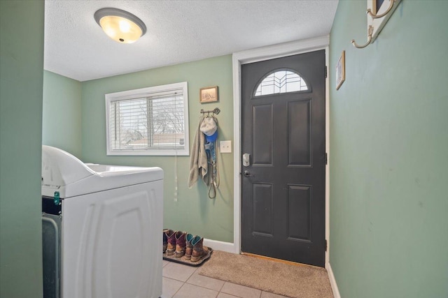 interior space with a healthy amount of sunlight, light tile patterned floors, a textured ceiling, and washer / clothes dryer