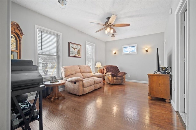 living room with ceiling fan, a healthy amount of sunlight, dark hardwood / wood-style flooring, and a textured ceiling