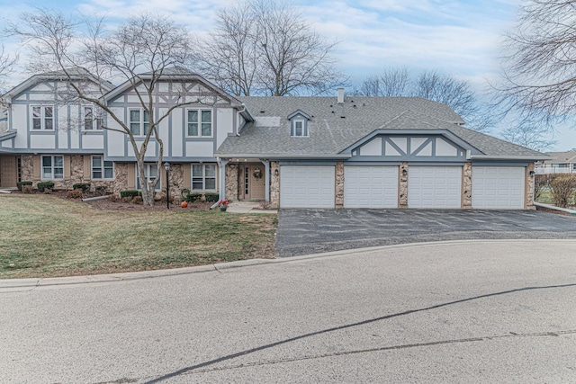 tudor-style house featuring a front yard and a garage